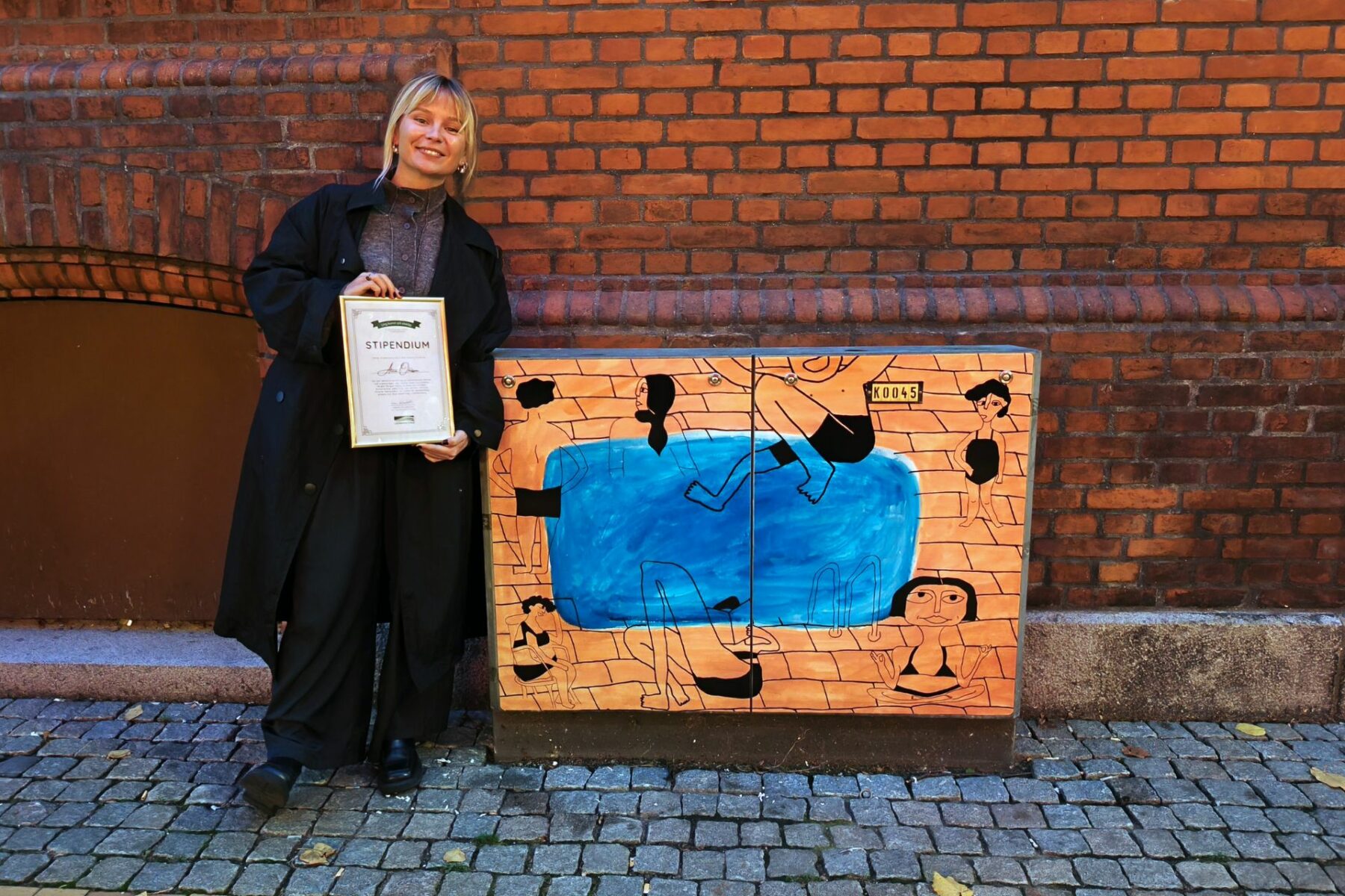Kvinna med stipendium vid målat elskåp med badmotiv