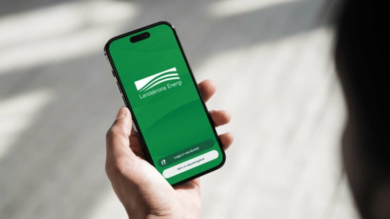 Hand håller mobil med Landskrona Energis inloggningssida