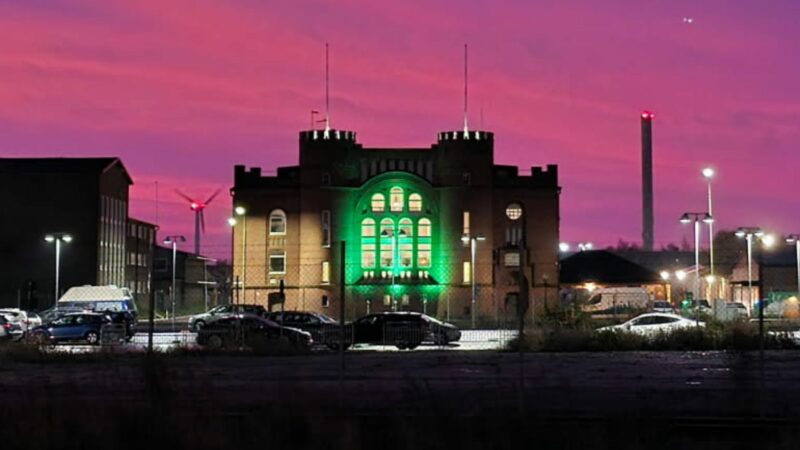 Byggnad upplyst i grönt mot rosa kvällshimmel