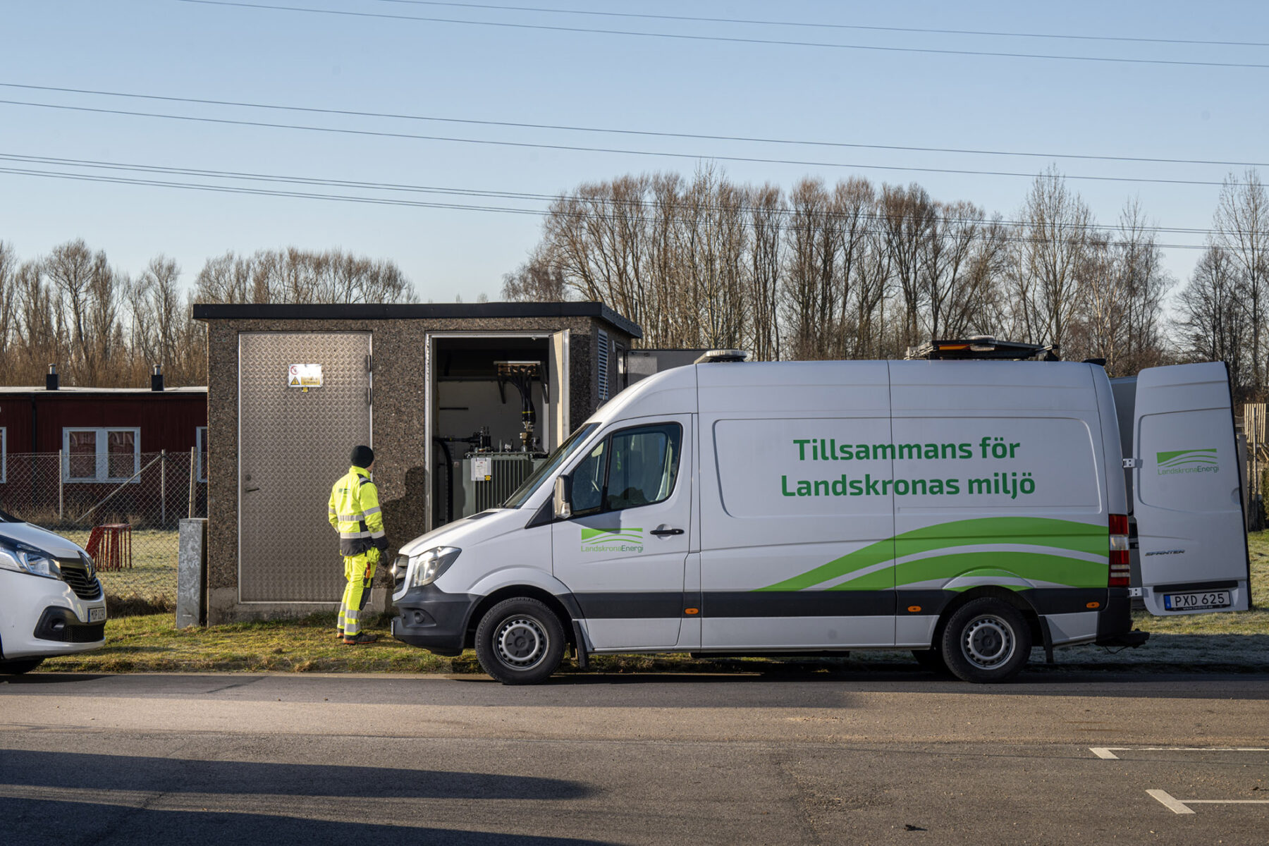 Servicebil vid elstation där en person i varselkläder arbetar.