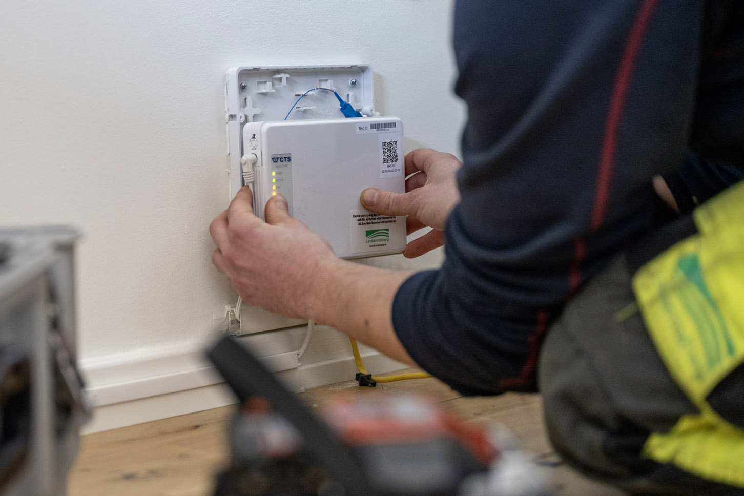 En tekniker installerar en ny fiberterminal på en vägg